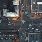 Aerial view of city intersection with many cars and GPS navigation system symbols. Autonomous driverless vehicles in city traffic. Future transportation concept